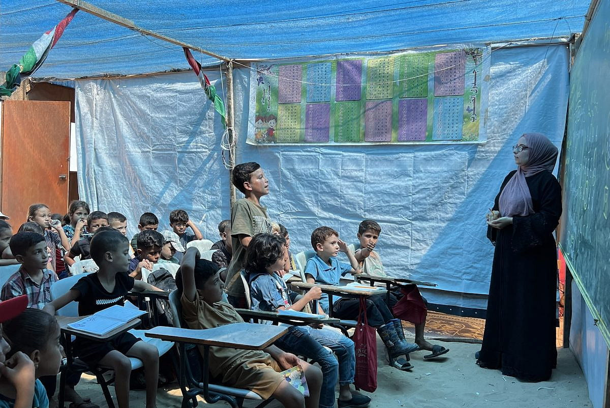 Teacher Alaa Abu Mustafa gives lessons at a tent school built over her destroyed home.
